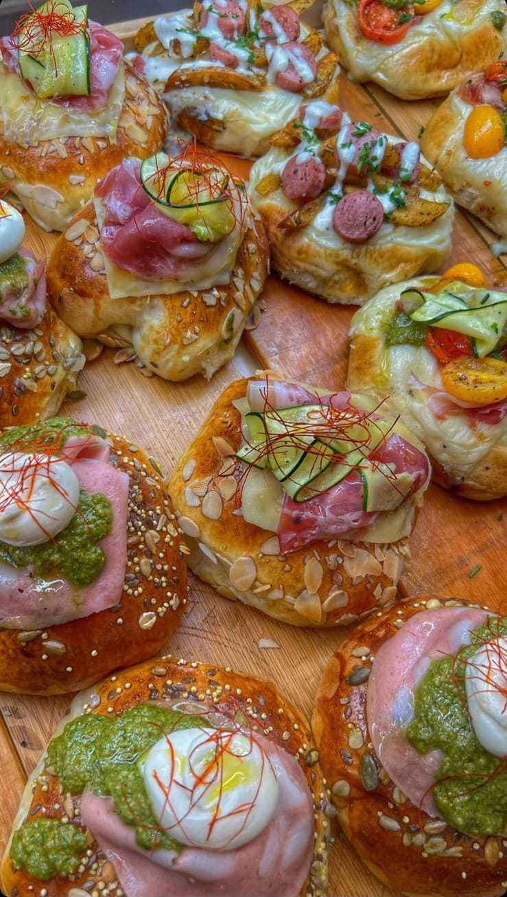 Tagliere di panini ai semi e focaccine farcite: mortadella, formaggio fresco, pesto, zucchine, pomodorini e patate.